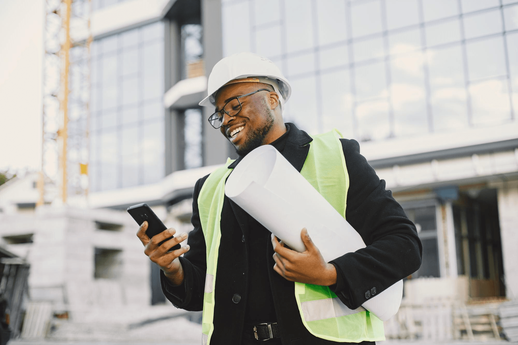 Site foreman reviewing drawings in front of a completed building